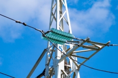 Line insulator on the electrical wires of a high-voltage tower.